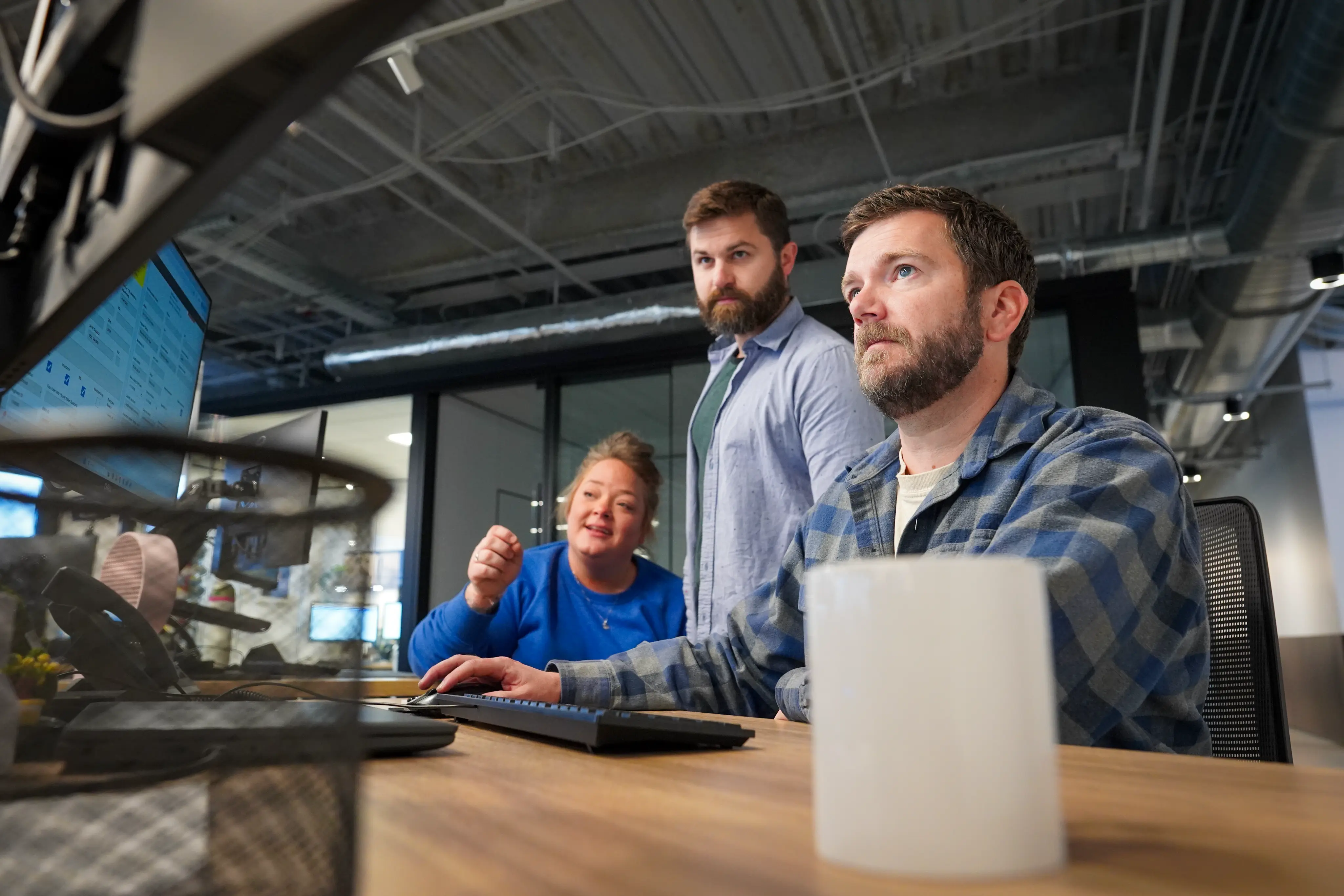 Three people looking at monitors in an office